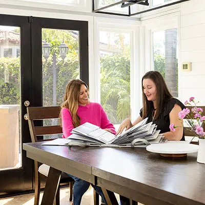 Two ladies smiling and looking through design book 