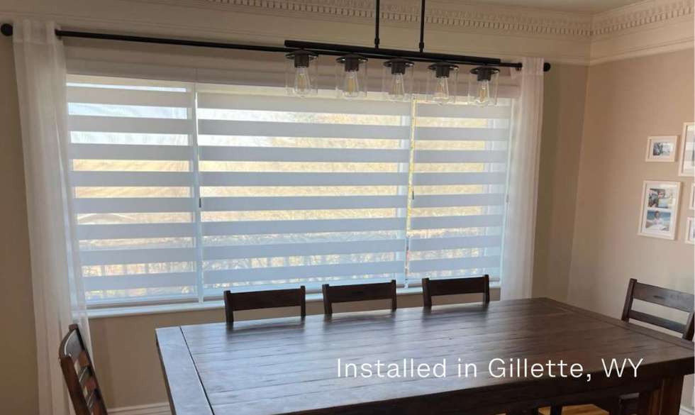 A white dual Sheer shade on a dining room window paired with white draperies on either side in Gillette Wyoming.