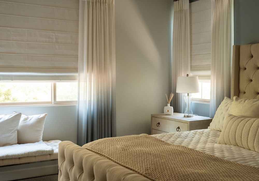 Roman Shades Layered with Sheer Drapes in a Bedroom