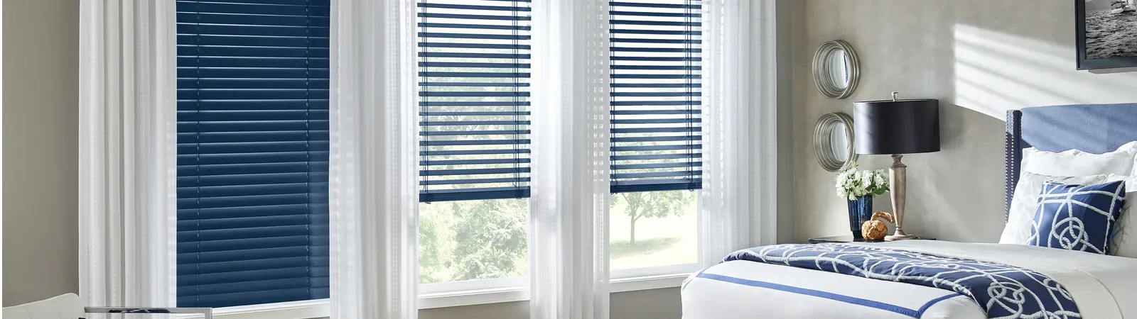 blue blinds and white drapes in a gray bedroom with blue accent
