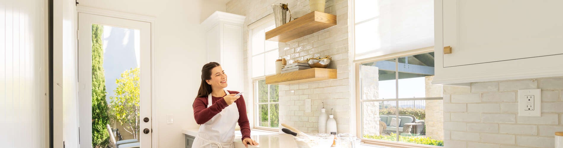 woman operating motorized roller shades in kitchen nook